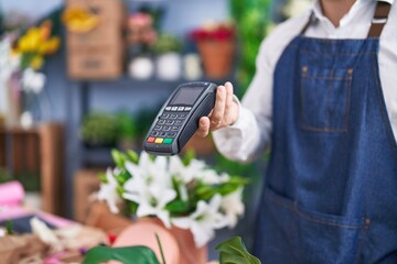 Young hispanic man florist holding dataphone at florist shop