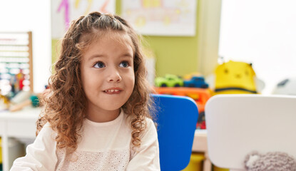 Fototapeta na wymiar Adorable blonde toddler smiling confident sitting on chair at kindergarten