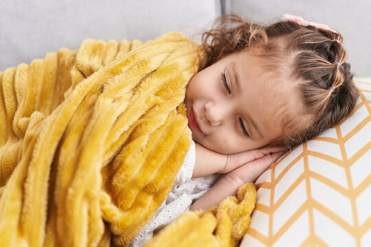 Adorable blonde toddler lying on sofa sleeping at home