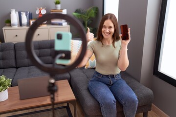 Fototapeta na wymiar Beautiful brunette woman recording vlog tutorial with smartphone at home smiling happy and positive, thumb up doing excellent and approval sign