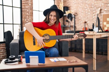 Young woman musician having online classical guitar lesson at music studio