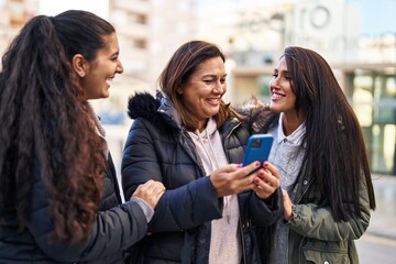 Three woman mother and daughters using smartphone at street