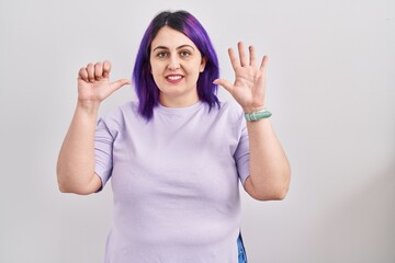 Plus size woman wit purple hair standing over isolated background showing and pointing up with fingers number six while smiling confident and happy.