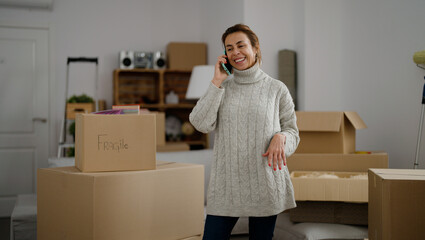 Middle age hispanic woman smiling confident talking on the smartphone at new home