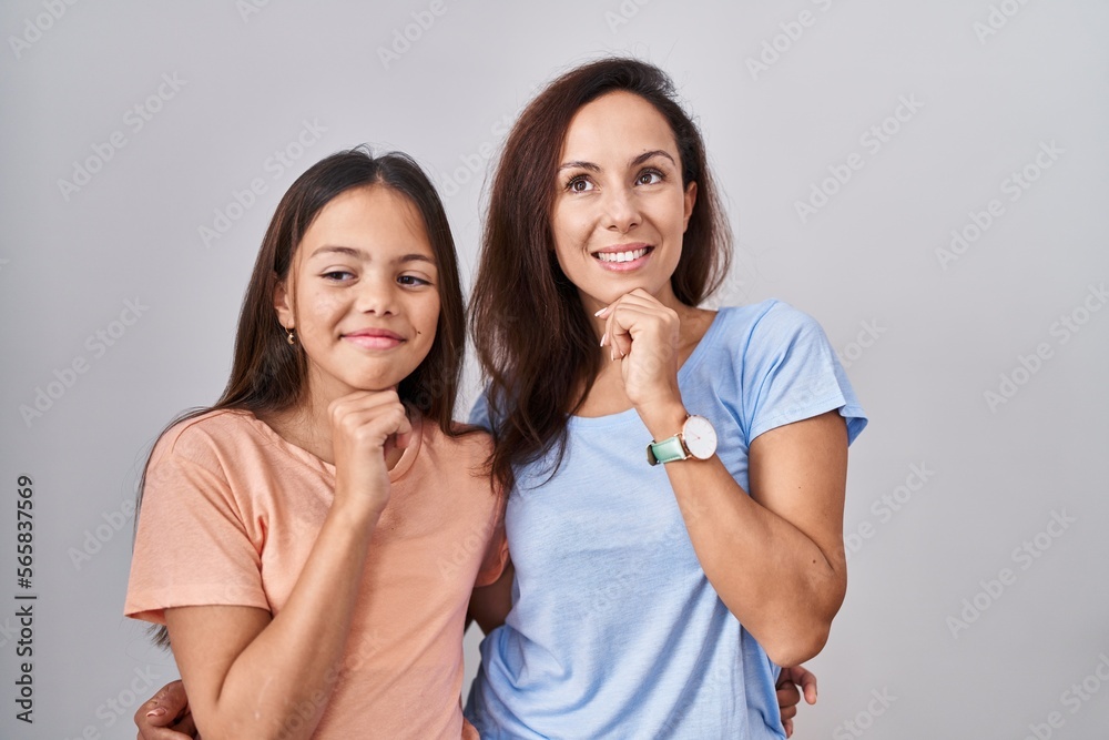 Sticker Young mother and daughter standing over white background with hand on chin thinking about question, pensive expression. smiling and thoughtful face. doubt concept.