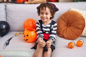 Adorable hispanic boy having halloween party holding pumpkin basket at home