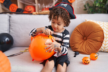 Adorable hispanic boy having halloween party drawing on balloon at home
