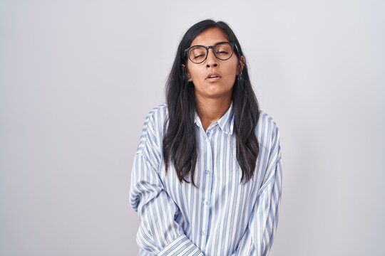 Young hispanic woman wearing glasses looking sleepy and tired, exhausted for fatigue and hangover, lazy eyes in the morning.
