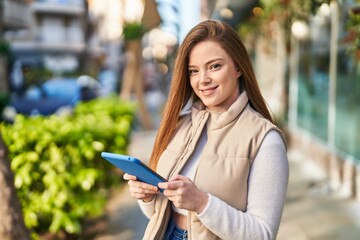 Obraz premium Young blonde woman smiling confident using touchpad at street