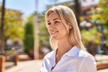 Young blonde woman smiling confident standing at park