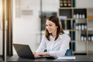 Confident Asian woman with a smile standing holding notepad and tablet at the modern office.