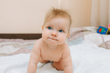 a funny baby crawling in the nursery at home. the baby is 6 months old learning to crawl