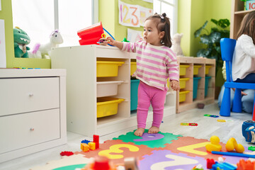 Adorable chinese toddler standing with relaxed expression at kindergarten