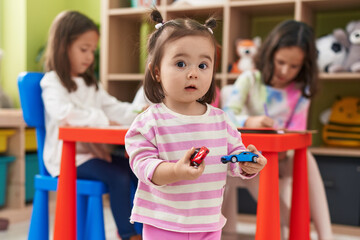 Group of kids preschool students drawing on paper holding cars toy at kindergarten