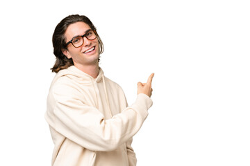 Young caucasian man isolated on green chroma background pointing back