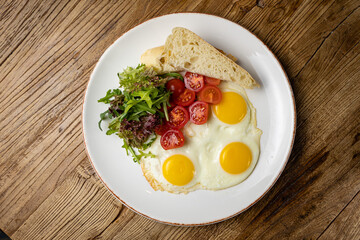 a delicious breakfast on a plate prepared in the restaurant. Fried eggs with tomatoes and salad
