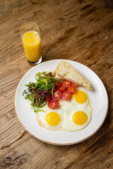 a delicious breakfast on a plate prepared in the restaurant. Fried eggs with tomatoes and salad
