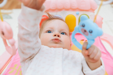 Adorable baby toddler lying on a colorful children's play mat with toys. Space for early development and activity of the child. baby 6 months