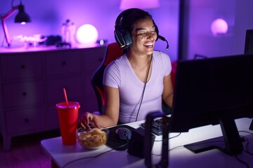 Young beautiful hispanic woman streamer playing video game at gaming room