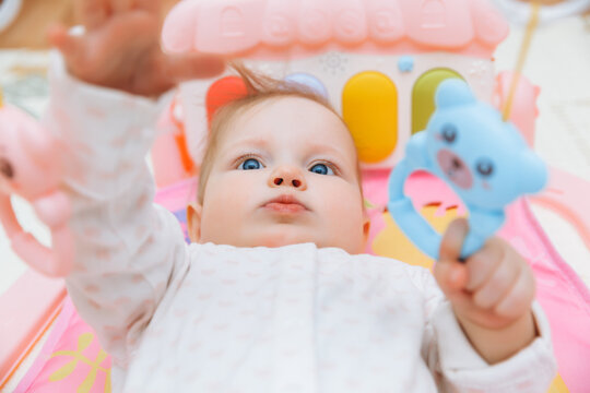 Adorable baby toddler lying on a colorful children's play mat with toys. Space for early development and activity of the child. baby 6 months