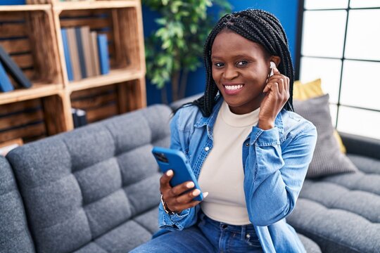 African american woman listening to music sitting on sofa at home