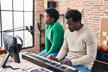 African american man and woman music group singing song playing keyboard piano at music studio