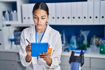 Young african american woman scientist write on touchpad at laboratory