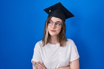 Blonde caucasian woman wearing graduation cap smiling looking to the side and staring away thinking.
