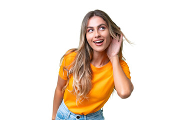 Young Uruguayan woman over isolated background listening to something by putting hand on the ear - obrazy, fototapety, plakaty