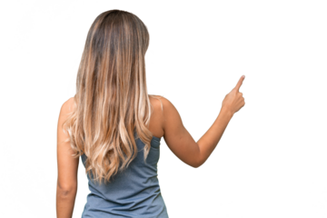 Young pretty sport Uruguayan woman with medals over isolated background pointing back with the index finger