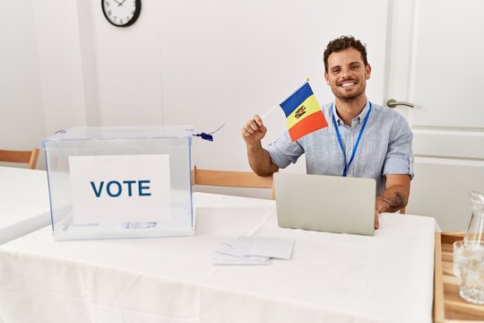 Young hispanic man smiling confident holding moldova flag working at electoral college