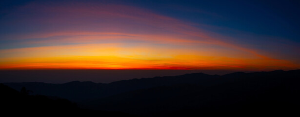 Panorama Aerial view sunset , sunrise over dark mountain with fog over the ground.The early evening sun illuminates the mountains and valleys.