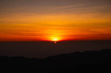 Panorama Aerial view sunset , sunrise over dark mountain with fog over the ground.The early evening sun illuminates the mountains and valleys.