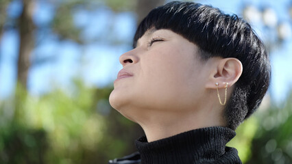 Young chinese woman breathing with closed eyes at park