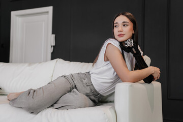 Focused hispanic young pretty woman leaning on bionic artificial hand, laying on sofa looks away...