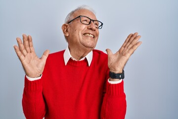 Fototapeta premium Senior man with grey hair standing over isolated background celebrating surprised and amazed for success with arms raised and eyes closed. winner concept.