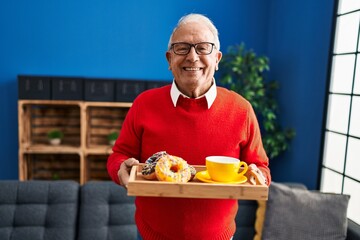 Senior man smiling confident holding tray with breakfast at home