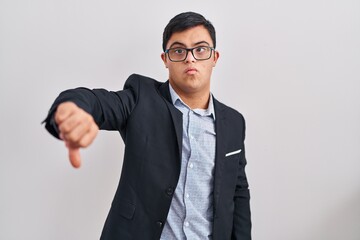 Young hispanic man with down syndrome wearing business style looking unhappy and angry showing...