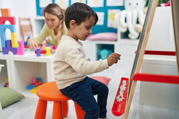 Teacher and toddler writing on blackboard at kindergarten
