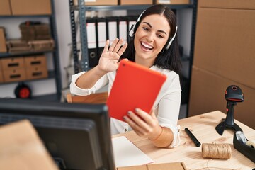 Young hispanic woman working at small business speaking on video call looking positive and happy standing and smiling with a confident smile showing teeth