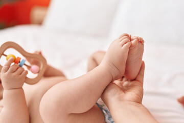 Adorable hispanic toddler lying on bed having feet massage at bedroom