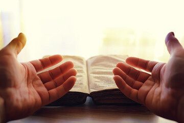 Praying with hand on bible black background. An old book with yellowed pages. Second-hand books.