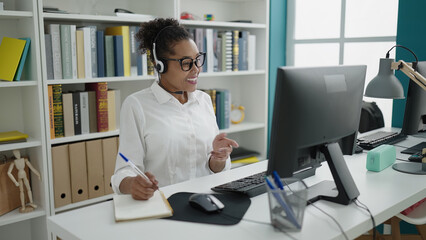 African american woman teacher having video call writing on notebook at library university