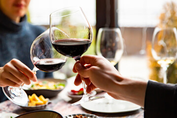 Close up of hands young couple clinking with glasses of red wine at restaurant
