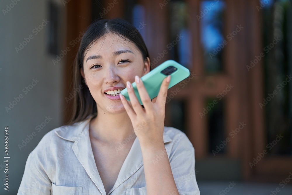 Wall mural chinese woman smiling confident talking on the smartphone at street