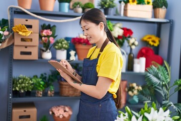 Chinese woman florist smiling confident writing on document at florist shop