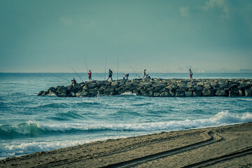 Pescadores sobre escollera del mar
