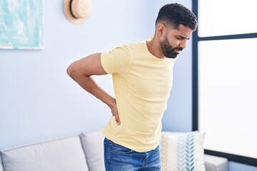 Young arab man suffering for backache standing at home