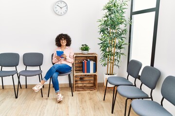 Young middle east woman using touchpad sitting on chair at waiting room