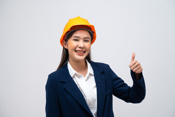 Portrait of Asian female engineer with hard hat posing show thumb up like gesture isolated on grey background.